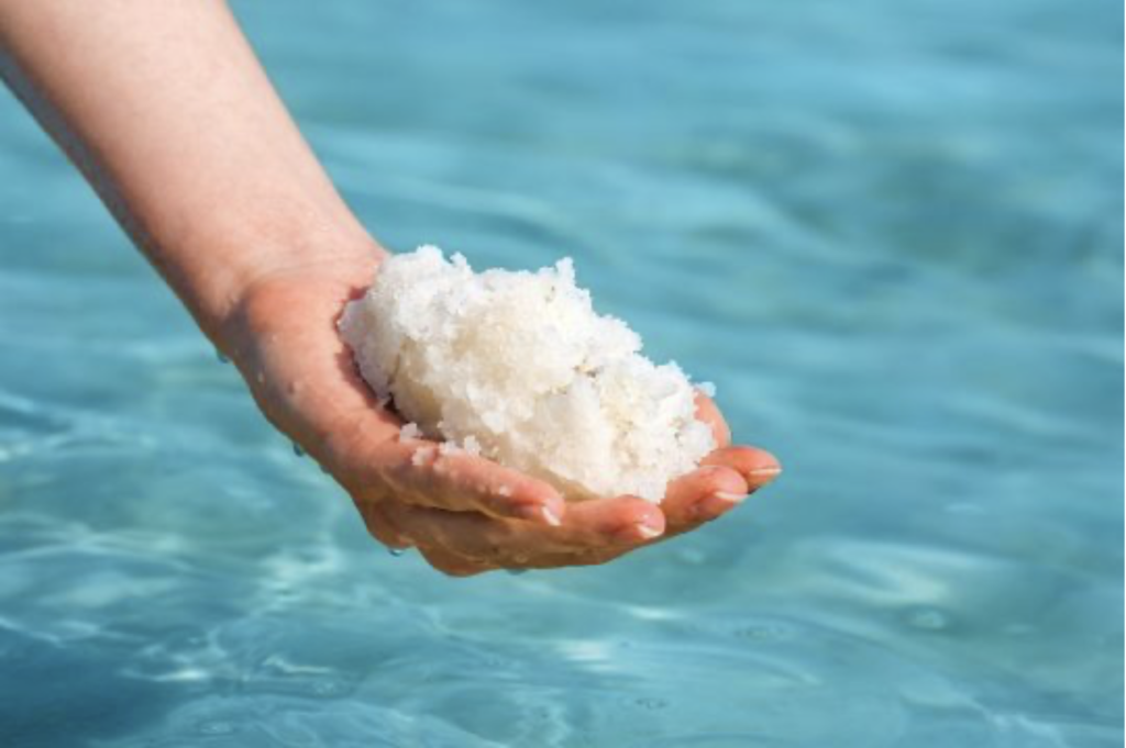 Close-up of sparkling Dead Sea salt crystals and white BHB powder arranged elegantly on a pure white background, representing the natural luxury ingredients in Leptozan natural fat burner